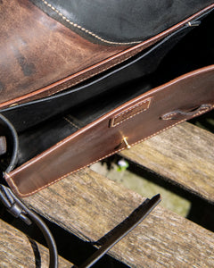 Oddity No. II crossbody bag with the dark leather flap open, revealing a 6cm deep main compartment and an internal slip pocket against the back panel.