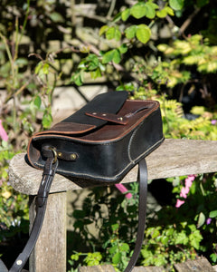 Side angle of a handmade heritage leather crossbody bag, highlighting the burnished edges, traditional saddle stitching, and adjustable vintage bridle rein strap.
